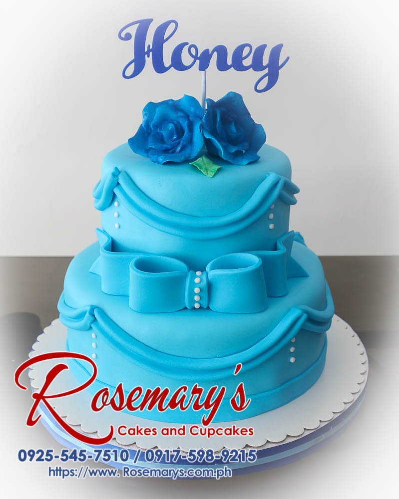 Delicious two-tier blue themed birthday cake adorned with a unique 3D printed topper, delicate ribbon, and a single rose. By Rosemary's Cakes (0925-545-7510)