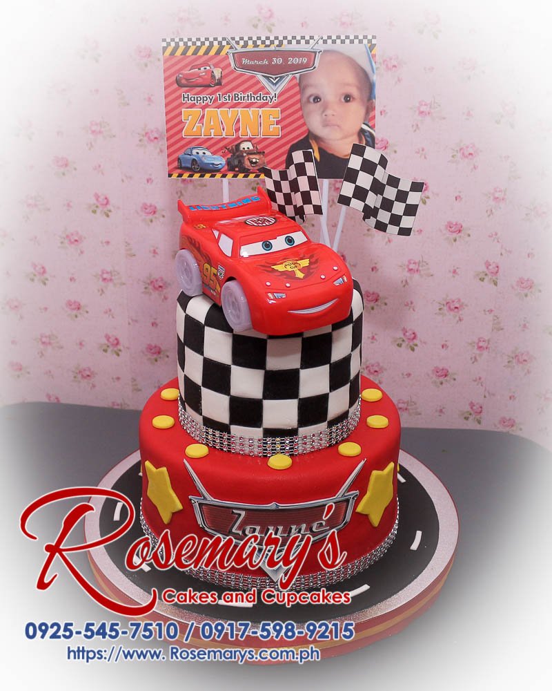 Delicious 2 layer Cars themed cake featuring Lightning McQueen, chequered design, vibrant red, from Rosemary's Cakes. Contact: 0917-598-9215.