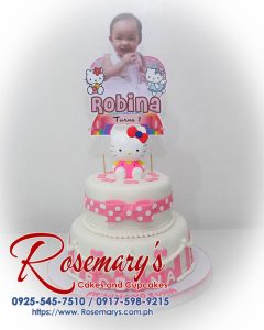 Two-tier Hello Kitty cake decorated with pink frosting, a white ribbon, and fondant details. Order your custom cake from Rosemary's Cakes! 0917-598-9215