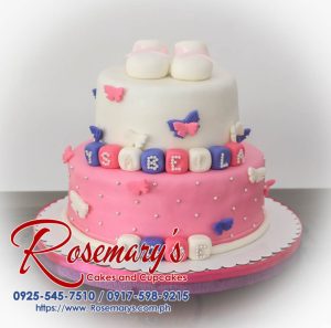 Two-tier pink and white christening cake adorned with fondant shoes and blocks. Custom cakes by Rosemary's Cakes: 0917-598-9215.