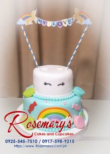 Two-tier rainbow cake adorned with a unicorn horn and colorful sprinkles. Perfect for magical celebrations! Rosemary's Cakes - 0925-545-7510