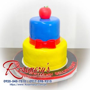 Two-layer cake with a "Snow White" theme featuring blue and red frosting accents and yellow decorative flowers. Order yours from Rosemary's Cakes: 0925-545-7510