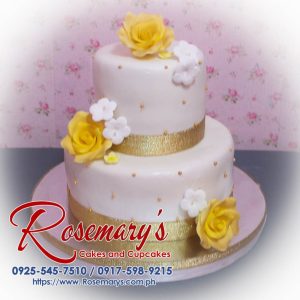 Elegant 2-layer white and gold wedding cake adorned with delicate flowers. Order from Rosemary's Cakes: 0917-598-9215.