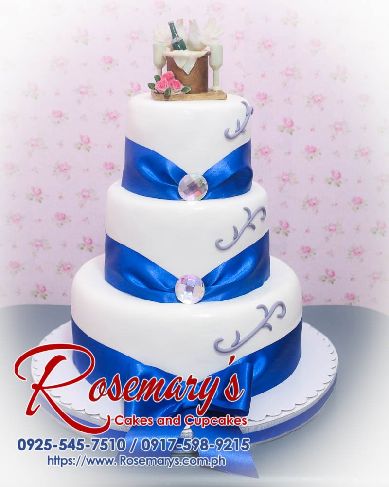 Delicious 3 layer blue and white wedding cake adorned with a ribbon, perfect for any themed celebration. Rosemary's Cakes, 0917-598-9215.