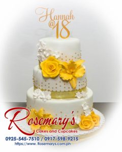 Three-tiered vanilla cake with smooth white frosting accented by edible gold leaf detailing. Perfect for any celebration! Order yours from Rosemary's Cakes: 0917-598-9215.