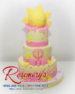 Three-tier yellow and pink birthday cake with a sunny design. Order your custom celebration cake from Rosemary's Cakes: 0925-545-7510.