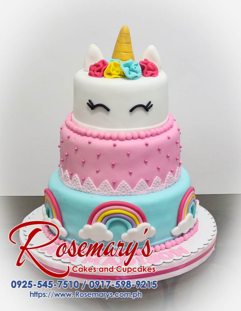 Three-tier pink and rainbow unicorn themed cake with edible gold accents. Custom cakes by Rosemary's Cakes. Call 0917-598-9215.
