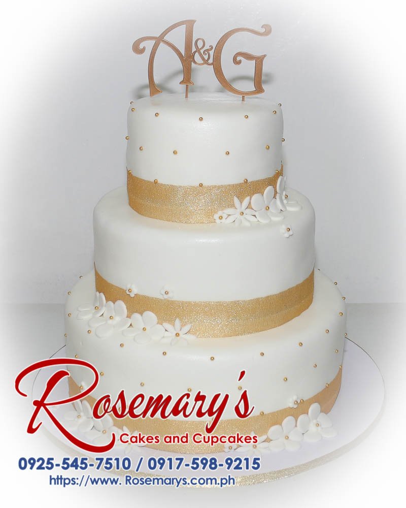 Delicious 3-tier white wedding cake with custom gold 