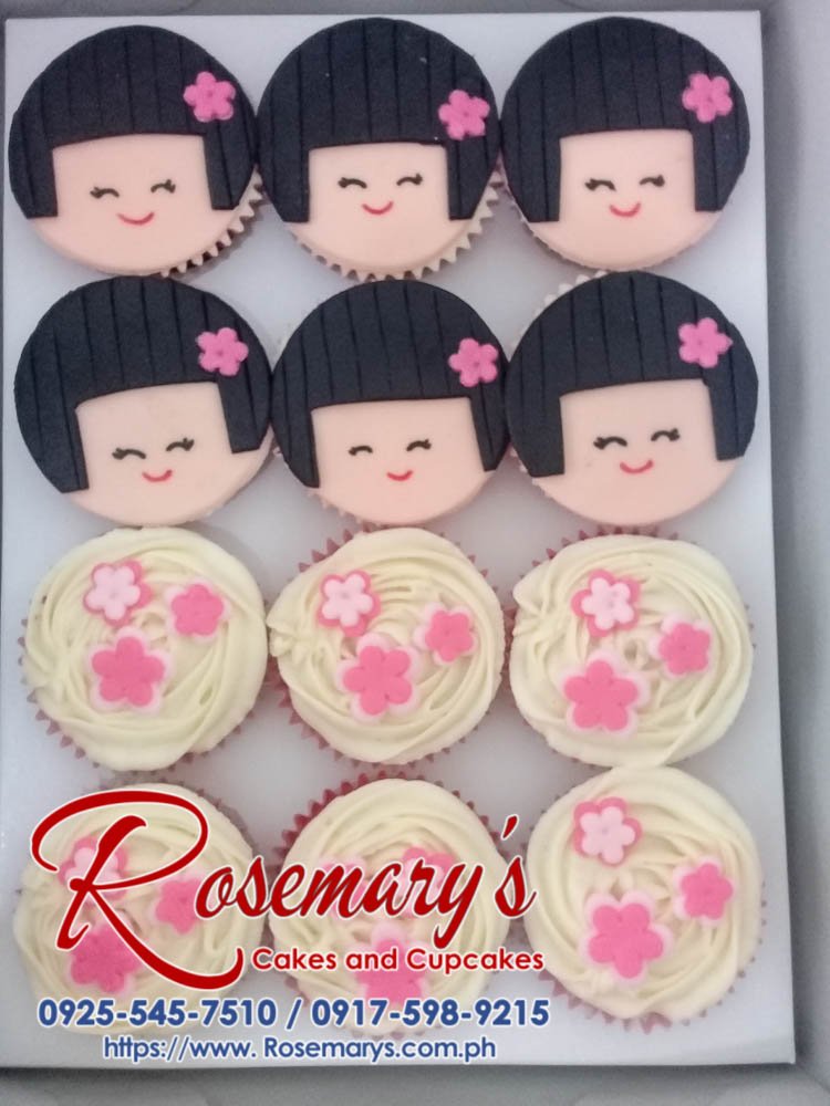 Delicate Japanese doll-themed cupcakes with buttercream frosting, fondant accents, and pastel colors. Crafted by Rosemary's Cakes. Call 0925-545-7510.