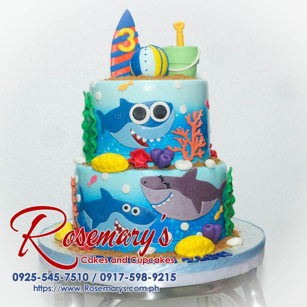 Delicious 2-layer Baby Shark themed cake by Rosemary's Cakes, featuring a vibrant blue design with a Shark Family under the sea. Contact: 0925-545-7510.